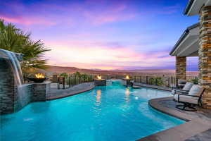 Pool at dusk with a mountain view, a patio area, pool water feature, and an outdoor fire pit