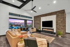 Living room with beamed ceiling, high vaulted ceiling, a premium fireplace, and ceiling fan