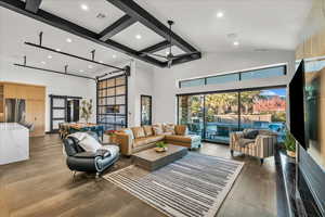 Living room featuring beam ceiling, ceiling fan, a barn door, and high vaulted ceiling