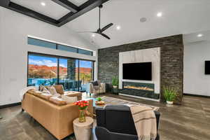 Living room with beamed ceiling, ceiling fan, a premium fireplace, and high vaulted ceiling