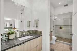 Bathroom with tile patterned flooring, vanity, toilet, and tiled shower