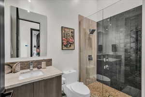 Bathroom featuring vanity, a shower with shower door, and toilet