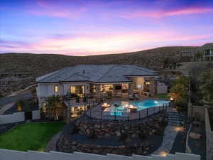 Pool at dusk featuring a yard, a fireplace, and a patio area