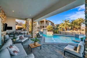 View of swimming pool with pool water feature, an outdoor living space, exterior kitchen, and a patio area