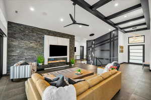 Tiled living room with beam ceiling, ceiling fan, and a towering ceiling