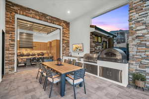 Patio terrace at dusk with an outdoor kitchen, area for grilling, and sink