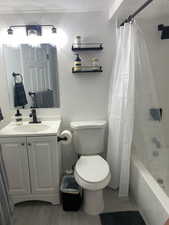 Full bathroom with vanity, toilet, a textured ceiling, and shower / bath combo with shower curtain