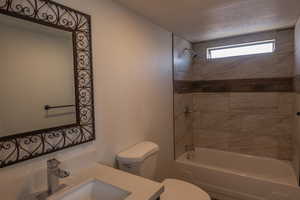 Full bathroom with vanity, toilet, and tiled shower / bath combo