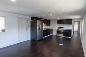 Kitchen with dark wood-type flooring, dark brown cabinets, stainless steel appliances, and a textured ceiling