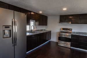 Kitchen featuring appliances with stainless steel finishes, dark hardwood / wood-style floors, sink, and dark brown cabinets