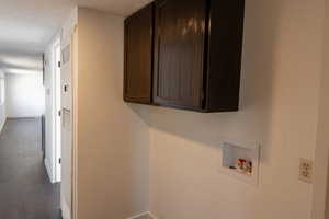 Laundry room with dark wood-type flooring, cabinets, washer hookup, and a textured ceiling