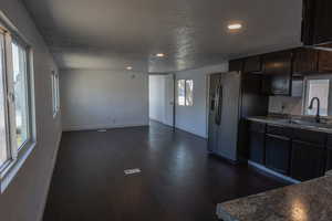 Kitchen featuring sink, stainless steel fridge, dark wood-type flooring, dark brown cabinets, and a textured ceiling