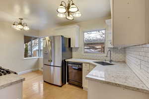 Kitchen featuring sink, decorative light fixtures, stainless steel fridge, black dishwasher, and a notable chandelier