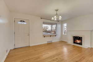 Entrance foyer with a tile fireplace, a notable chandelier, and light hardwood / wood-style flooring