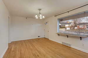 Unfurnished room featuring light hardwood / wood-style floors and a notable chandelier