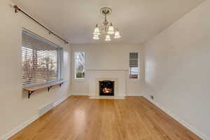 Unfurnished living room featuring an inviting chandelier and hardwood / wood-style flooring