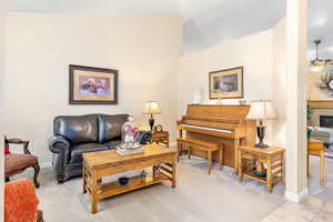 Living room with ceiling fan, lofted ceiling, light colored carpet, and a fireplace