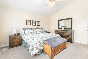 Primary bedroom featuring vaulted ceiling and ceiling fan