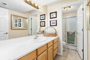 Basement, Bathroom with walk in shower, vanity, tile patterned floors, and toilet