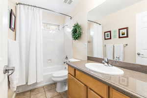 Full bathroom with shower / bath combination with curtain, vanity, toilet, and tile patterned flooring