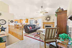 Carpeted living room featuring a tiled fireplace and ceiling fan