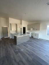 Kitchen with white cabinetry, LVP flooring, a kitchen island with sink, and a textured ceiling