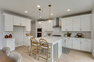 PHOTOS FROM SIMILAR HOME. COLORS & SELECTIONS WILL VARY. Kitchen with built in microwave, white cabinetry, wall chimney exhaust hood, and a center island with sink (alternate layout)