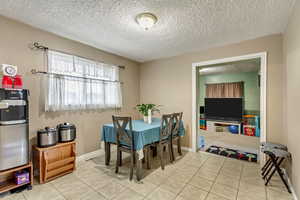 Dining space with light tile patterned floors and a textured ceiling