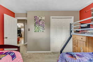 Bedroom featuring light carpet, a closet, and a textured ceiling