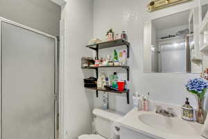 Bathroom with vanity, an enclosed shower, and toilet