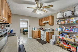 Kitchen featuring sink, ceiling fan, a textured ceiling, light tile patterned flooring, and white electric stove