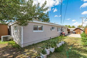 Rear view of house with cooling unit, a lawn, and a patio