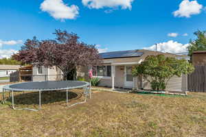 View of front of house with a front yard, a trampoline, and solar panels