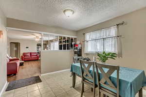 Dining area featuring light tile patterned floors, a textured ceiling, and ceiling fan