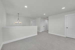 Unfurnished room featuring an inviting chandelier and light colored carpet