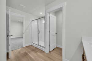 Bathroom featuring a shower with door, vanity, and hardwood / wood-style floors