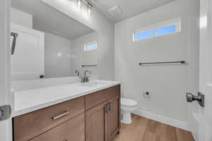 Bathroom with wood-type flooring, vanity, and toilet