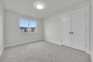 Unfurnished bedroom featuring light colored carpet, a closet, and a textured ceiling