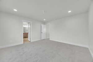 Unfurnished bedroom with light carpet and ensuite bath