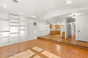 Unfurnished living room with sink, vaulted ceiling, and light hardwood / wood-style floors