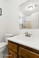 Bathroom with vanity, a shower with curtain, and toilet