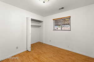 Unfurnished bedroom with a closet, a textured ceiling, and light hardwood / wood-style flooring