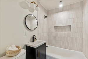 Full bathroom with tiled shower / bath, vanity, and toilet