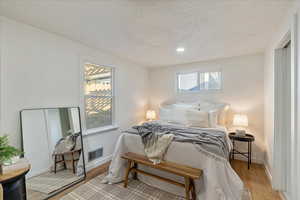 Bedroom with light hardwood / wood-style floors and a textured ceiling