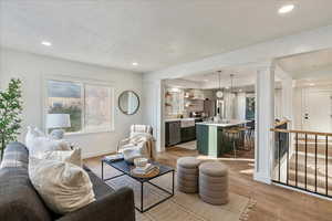 Living room featuring ornate columns, sink, a textured ceiling, and light hardwood / wood-style flooring