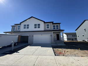 View of front facade featuring board and batten siding, driveway, and a garage