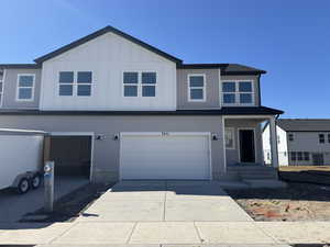 View of front of property with board and batten siding, concrete driveway, and a garage