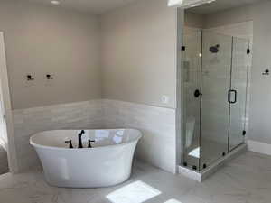 Bathroom with shower with separate bathtub and tile walls