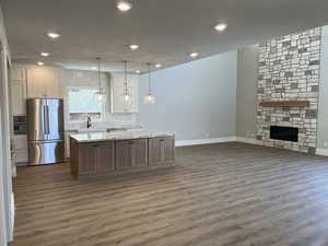 Kitchen with pendant lighting, white cabinetry, stainless steel refrigerator, and a kitchen island