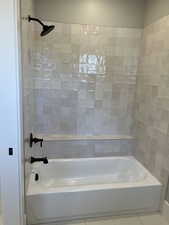 Bathroom featuring tiled shower / bath and tile patterned flooring